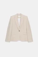 Blazer color beige de cuello solapa y manga larga. Tiene bolsillos con solapa en el delantero y cierre frontal con un botón.