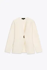 Chaqueta color crema de punto con escote en pico y manga larga. Cierre frontal con un botón dorado.