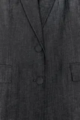 Blazer gris oscuro con cuello solapa, manga larga, bolsillos con solapa en el delantero y cierre frontal con dos botones forrados.