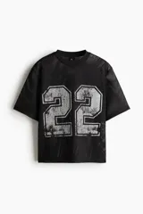 Remera negra de malla con cuello redondo ribeteado y estampado del número 22 en plateado. Corte oversized con hombros caídos y bajo recto.