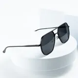 Lentes de sol estilo aviador con armazón metálico negro y lentes grises.