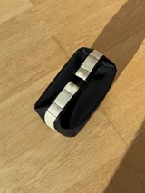 Neceser color beige de forma rectangular, con cierre superior y asa de mano.