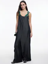 Mono largo de denim azul oscuro, con breteles finos regulables, escote recto, bolsillos traseros y corte amplio de pierna recta.