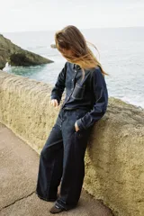 Pantalón de jean azul oscuro, de tiro medio, corte ancho y largo, estilo jogger con cintura elástica ajustable con cordones, bolsillos delanteros de vivo y bolsillos de parche en la espalda.