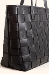 Cartera tipo tote bag de cuero vacuno trenzado a mano, con diseño de tejido ajedrez. Cuenta con doble asa de hombro y cierre superior.