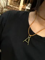 Collar con cadena de tiento y colgante de letra en bronce, diseño minimalista.