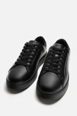 Zapatillas urbanas de cuero sintético color negro, con cordones y suela chunky.