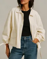 Chaqueta color blanco con cierre frontal, cuello camisero, bolsillos delanteros y mangas largas con lazos en los puños.