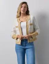 Chaqueta Nanette en tejido tweed color blanco y denim color beige. Cuello a la base y abertura central. Delantera con bolsillos. Puño con aplique de botones perlados. Terminación desflecada. Forro interno.