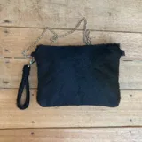 Sobre negro de cuero vacuno con forro interior y bolsillo interno. Incluye correa de cadena desmontable y agarradera de cuero.