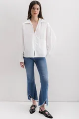 Camisa blanca de algodón con cuello clásico, mangas largas con puños abotonados y bolsillo de parche en el frente.