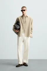 Camisa de manga larga color celeste claro, con cuello solapa y cierre frontal de botonadura. Presenta una textura sutil en el tejido.