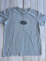 Remera celeste de corte clásico con cuello redondo y manga corta. Estampado pequeño en el frente de una hoja estilizada en color gris oscuro.