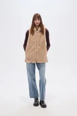 Chaleco sin mangas de pelo sintético color beige claro, con capucha y cierre frontal.