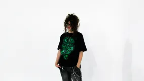 Remera negra de corte regular fit, confeccionada en jersey de algodón grueso. Estampa frontal con diseño de cruz y calaveras en color verde.