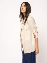 Blazer oversized de corte recto, color beige, con tejido de lino bordado y largo a la cadera. Incluye hombreras finitas y bolsillos delanteros.