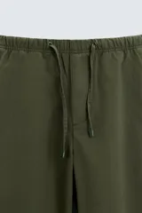 Pantalón verde militar de corte carrot fit, confeccionado en tejido de algodón. Cuenta con cintura elástica ajustable con cordón, bolsillos frontales y un bolsillo trasero de plastrón.