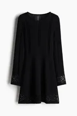 Vestido mini negro de manga larga en tejido de punto suave con escote redondo y falda con leve vuelo. Presenta secciones caladas en mangas, delantero y espalda, y secciones en punto pointelle en puños y bajo.