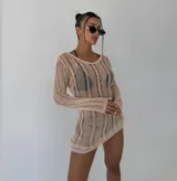 Vestido corto de punto calado color negro, con cuello redondo y mangas largas. Presenta un diseño semi-transparente de silueta ajustada.