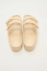 Sandalias planas color beige con doble tira y hebillas ajustables.