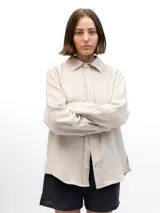 Camisa de lino beige de manga larga, corte clásico y holgado, con cuello camisero y cierre frontal con botones.