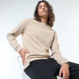 Buzo color beige liso de cuello redondo y manga larga con puños y ruedo acanalados.