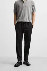 Pantalón color arena de corte recto, confeccionado en tejido elástico. Cuenta con cintura elástica ajustable con cordón, bolsillos laterales y bolsillos de vivo en la parte trasera.
