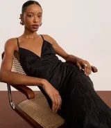 Vestido midi de satén negro con textura jacquard, escote en V, tirantes finos regulables y godets en el ruedo.