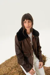 Chaqueta marrón de cuero con cuello de piel sintética negra, cierre con botones a presión, bolsillos con solapa y corte a la cintura.