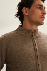 Campera de lana color crema, tejida con cierre delantero, cuello alto y bolsillos delanteros.