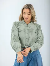 Camisa color crema de broderie, corte holgado, con cuello mao y mangas largas abullonadas con bordados florales.
