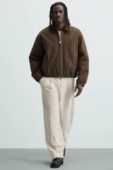 Pantalón de vestir color beige, corte wide fit, con cintura elástica, pliegues frontales, bolsillos laterales y traseros de vivo.