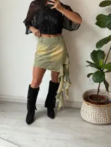 Minifalda de denim verde con detalles de desteñido amarillo y ruedo irregular con flecos.