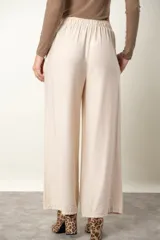 Pantalón palazzo de viscosa y lino color beige claro satinado, con cintura elastizada y bolsillos laterales.