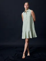Vestido corto blanco de gasa, sin mangas, con cuello camisero, abertura central con botones y terminación de ruedo con volado.
