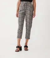 Pantalón capri con estampado tipo tweed en tonos blanco, negro y gris. Tiene corte recto, cintura alta con lazo y bolsillos laterales.