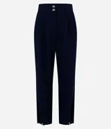 Pantalón de vestir azul marino, de corte carrot, con pliegues delanteros, detalle de botones en la cintura y aberturas en el bajo.