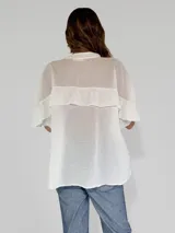 Camisa color amarillo con cuello clásico, cierre frontal con botones y mangas cortas con volados.