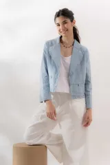 Blazer celeste de denim 100% algodón, entallado y corto a la cadera, con cuello y solapa amplios, mini bolsillos delanteros y bordado con el logo de la marca en el interior del puño.