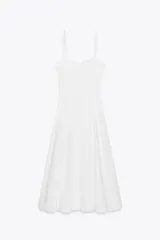 Vestido midi blanco de popelín con escote corazón y volantes. Tiene tirantes finos con detalle de lazo, forro interior combinado y cierre lateral con cremallera oculta.