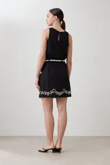 Minifalda negra de tiro alto con bordado blanco en el ruedo y cinturón de soga.