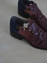 Sandalias mallorquinas de gamuza color verde azulado con tiras entrecruzadas y hebilla dorada al tobillo.