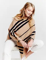 Poncho de tejido color beige con cuello alto y rayas diagonales anchas en azul marino. Presenta mangas largas y terminación asimétrica.