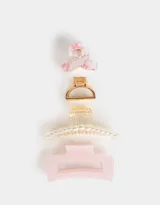 Set de cuatro broches para el pelo de diferentes formas y colores: uno transparente con estampado de flores rosas, uno dorado, uno transparente con perlas y uno rosa.