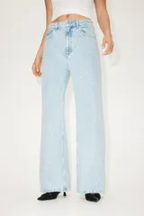 Pantalón jean de tiro bajo en denim bouclé celeste, de algodón rígido, con cinco bolsillos, cierre con botón y corte holgado con piernas amplias.