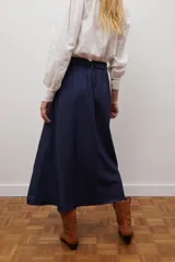 Falda larga de jean azul oscuro, corte acampanado con paneles y costuras visibles.