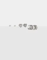 Set de tres pares de aros bañados en plata, con distintos diseños: un par de aros tipo botón con strass, un par de aros con forma de corazón calado y un par de aros tipo argolla con diseño trenzado.