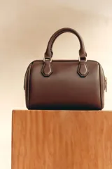 Bolso marrón formato city con asa doble de mano con detalles metálicos y correa interior extraíble en tejido canvas con posición bandolera. Bolsillo interior con cierre mediante cremallera metálica.