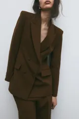 Blazer marrón de cuello solapa y manga larga. Bolsillos con solapa en delantero y cierre frontal cruzado con botones forrados.