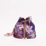 Cartera tipo saco o 'bucket bag' de tela color lila, decorada con bordados florales y lentejuelas en tonos morados, plateados y burdeos. Posee un cierre de cordón dorado con borlas de perlas y una correa de hombro de cadena dorada entrelazada con material rosa.